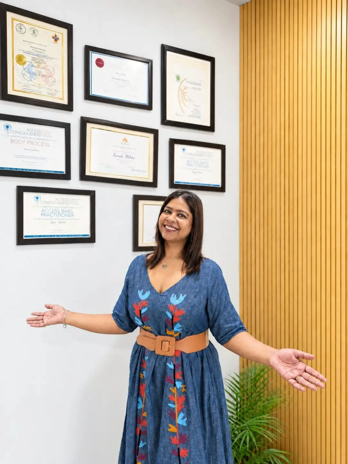Sonali Mittra at The Healing Room, in front of her framed therapy certifications